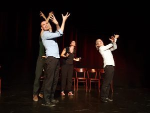 Three improvisers looking up, arms in the air